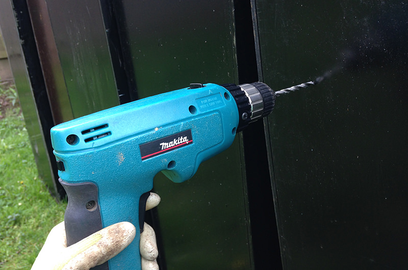 a man drilling drainage holes in cabinat